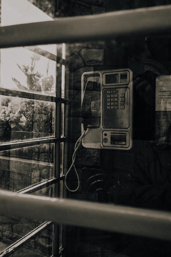Retro telephone booth interior with an old-fashioned payphone, captured in a sepia tone for a nostalgic feel.